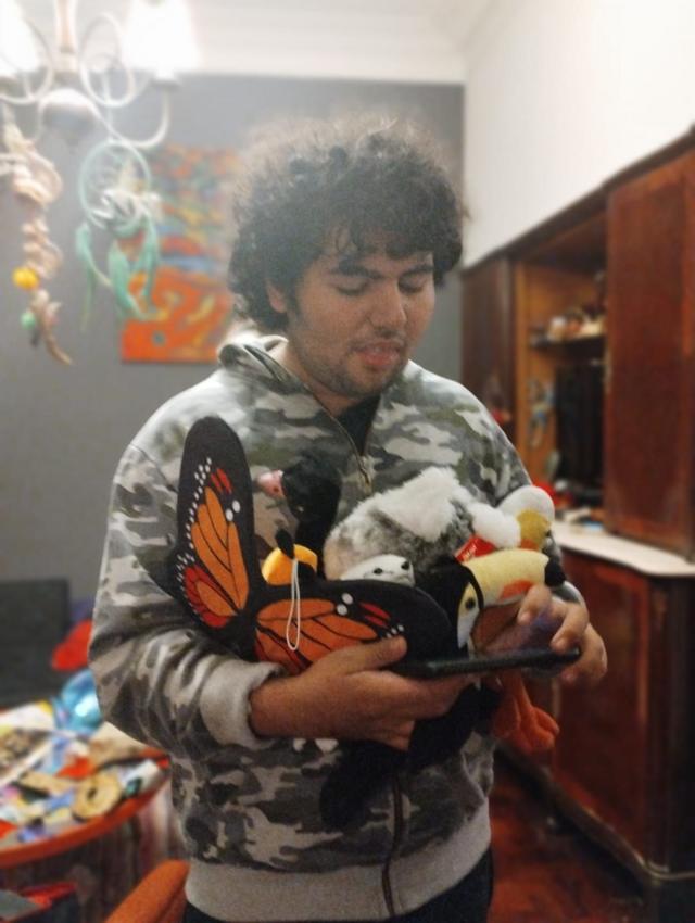 Vicente con algunos de sus peluches sosteniendo un teléfono.