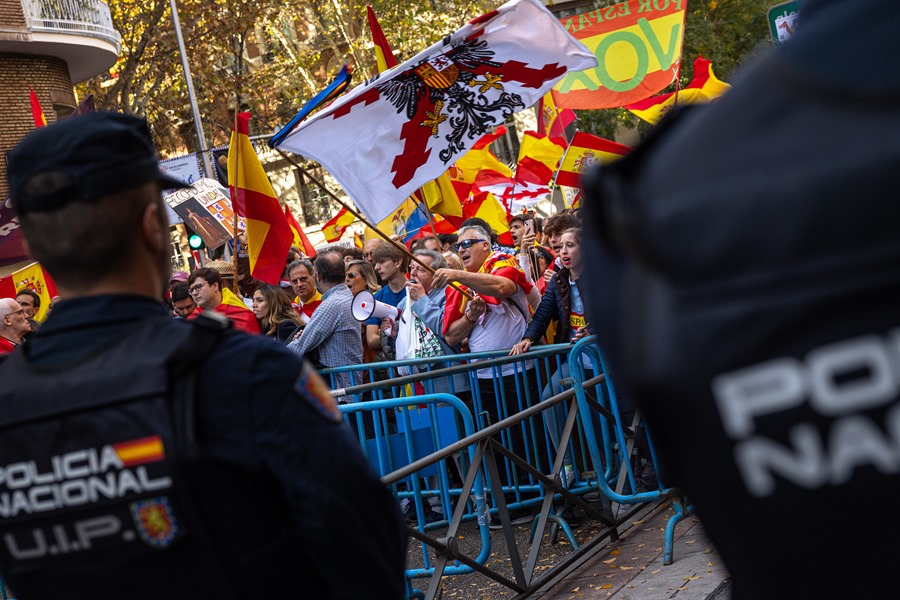 Manifestantes enarbolan banderas frente a agentes de la policía nacional este sábado en las inmediaciones de la sede del PSOE en la madrileña calle de Ferraz