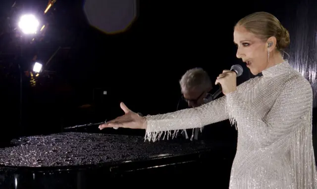 Céline Dion cantando en un escenario montado en la Torre Eiffel.
