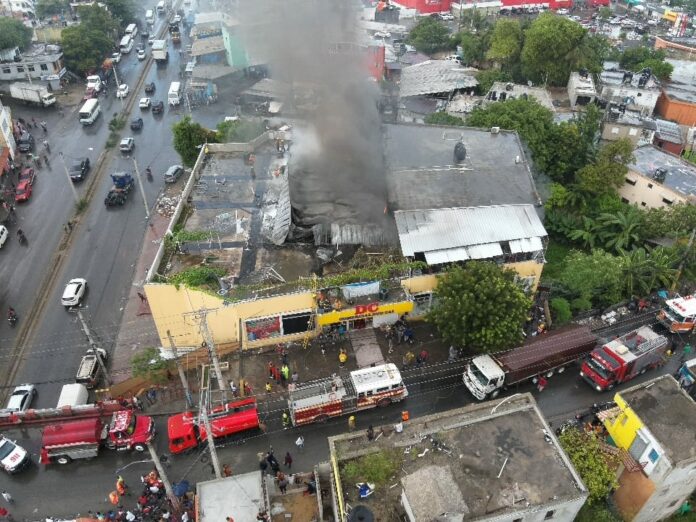 Sistema 911 coordina asistencia en incendio de tienda en Bajos de Haina; hay dos bomberos afectados